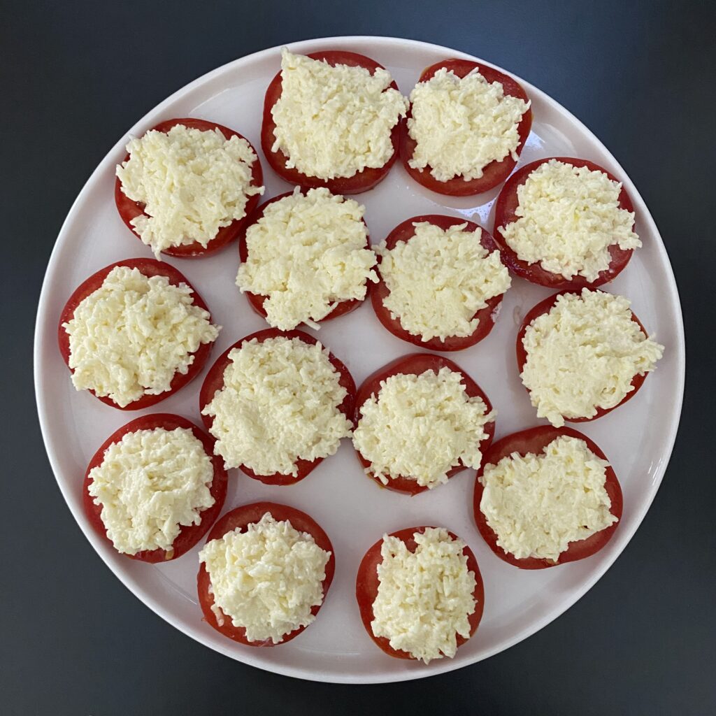 Выложить сыр с чесноком и майонезом на помидоры